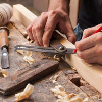 schrijnwerker bewerkt hout en tekent de maten af